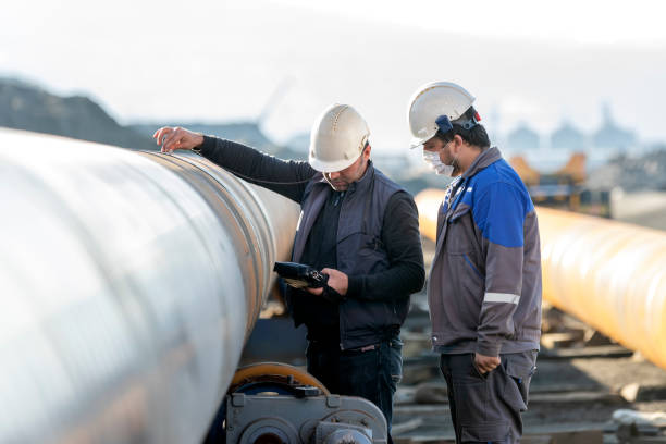 Image of two person whose inspecting a big pipeline through ndt equipment.